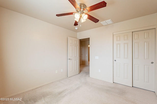 unfurnished bedroom with baseboards, visible vents, a ceiling fan, light carpet, and a closet
