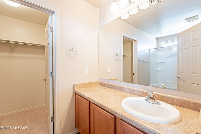 full bath with a walk in closet, visible vents, vanity, and walk in shower
