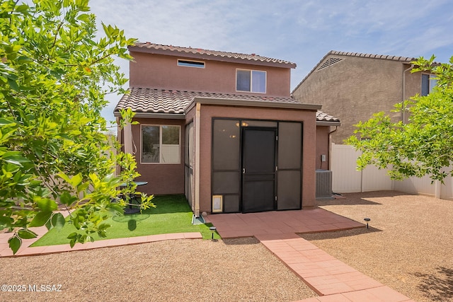 rear view of house featuring a tiled roof, stucco siding, fence, and a patio