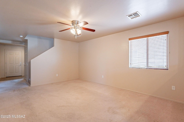 carpeted spare room with visible vents and ceiling fan