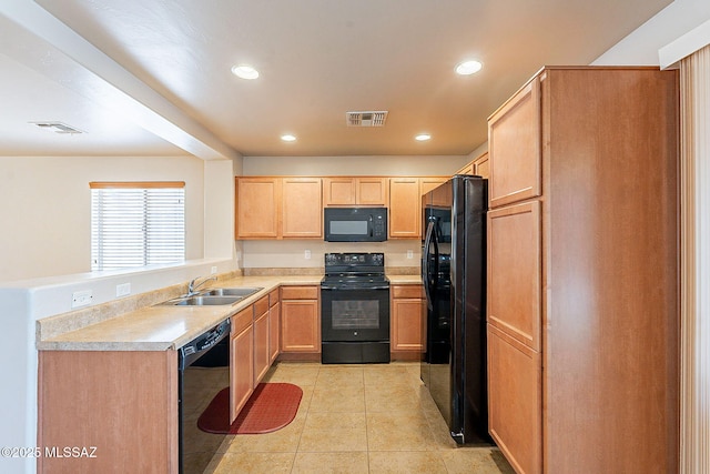 kitchen featuring visible vents, black appliances, a sink, and light brown cabinets