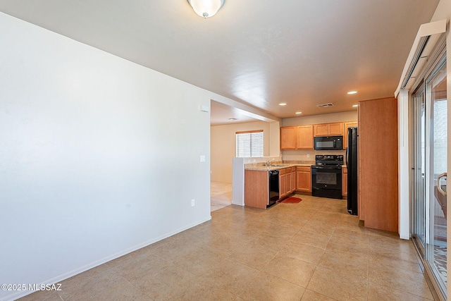 kitchen featuring plenty of natural light, black appliances, light countertops, and a sink