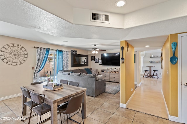 dining space featuring light tile patterned floors, visible vents, a textured ceiling, and a ceiling fan