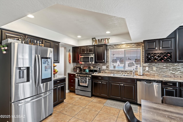 kitchen with a sink, stainless steel appliances, light tile patterned flooring, and decorative backsplash