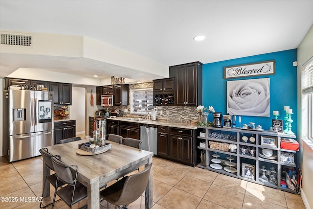 kitchen featuring visible vents, a sink, backsplash, stainless steel appliances, and dark brown cabinets