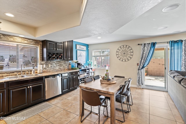 kitchen with dishwasher, light tile patterned floors, backsplash, and a sink