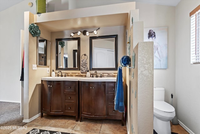 bathroom featuring a sink, baseboards, toilet, and double vanity