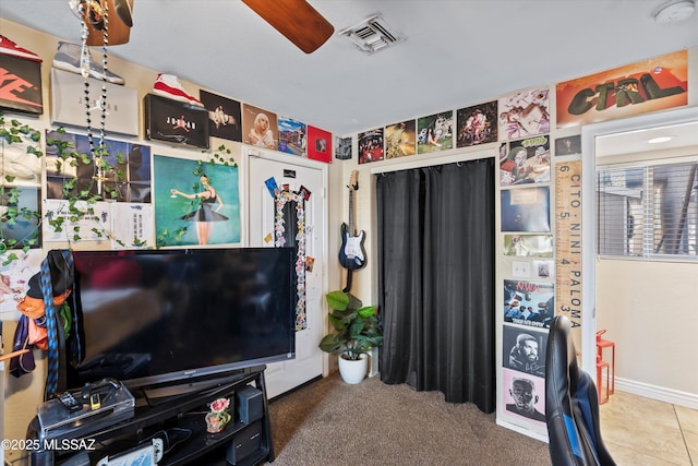 interior space featuring tile patterned flooring, visible vents, ceiling fan, and carpet floors