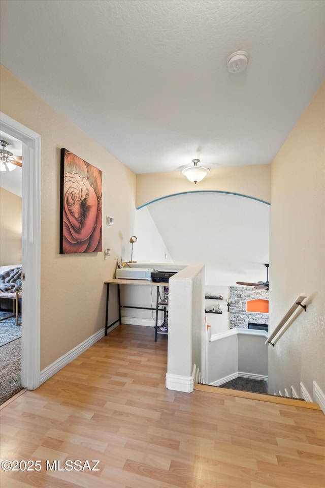 stairway featuring baseboards, ceiling fan, and wood finished floors