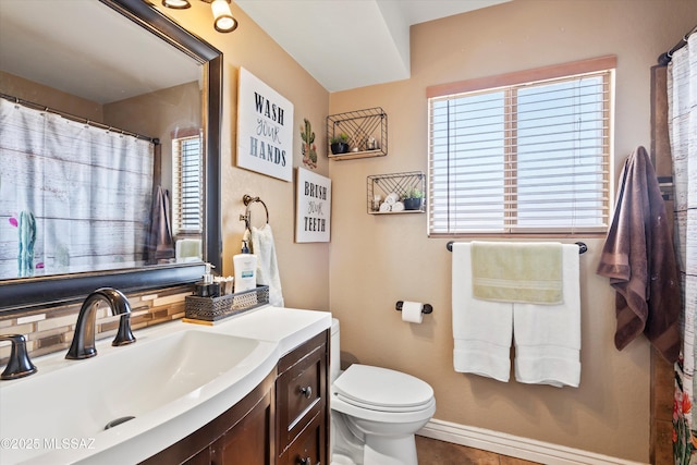 bathroom featuring baseboards, tasteful backsplash, toilet, and vanity