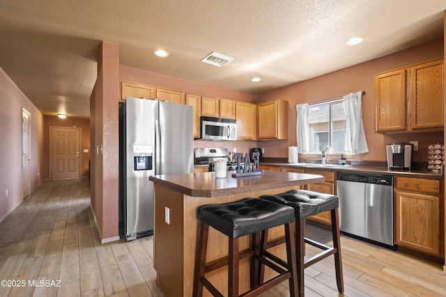 kitchen with visible vents, dark countertops, a kitchen island, and appliances with stainless steel finishes