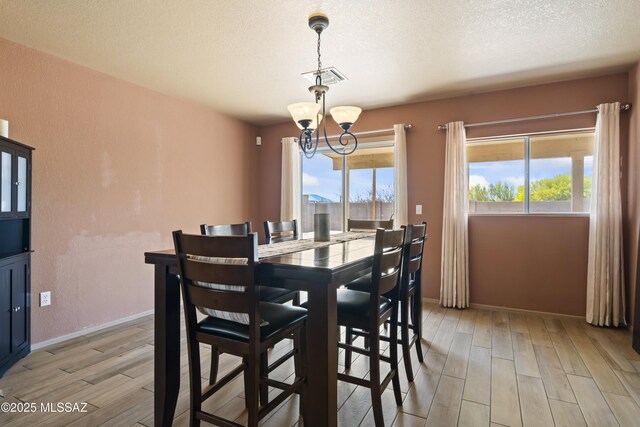 dining area featuring a healthy amount of sunlight, light wood-style floors, a chandelier, and visible vents