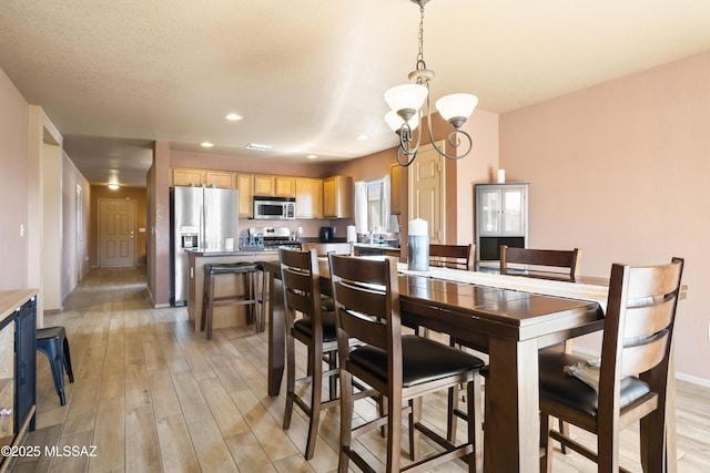 dining space featuring baseboards, light wood-type flooring, recessed lighting, and a chandelier