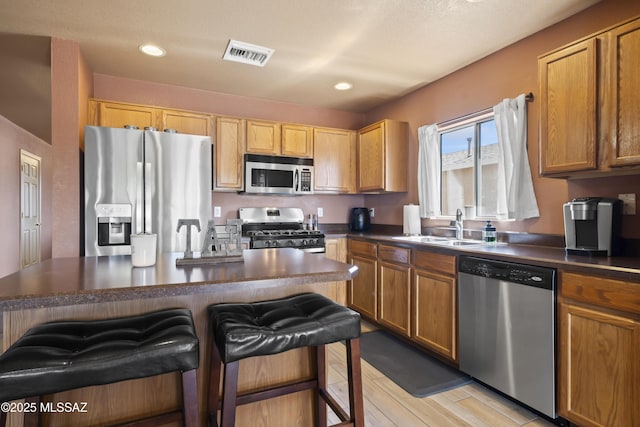 kitchen with a sink, dark countertops, appliances with stainless steel finishes, and visible vents