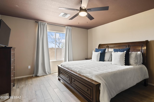 bedroom featuring light wood-style flooring, baseboards, ceiling fan, and visible vents