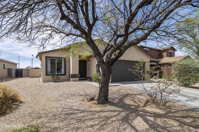 view of front facade with stucco siding, a garage, fence, and concrete driveway