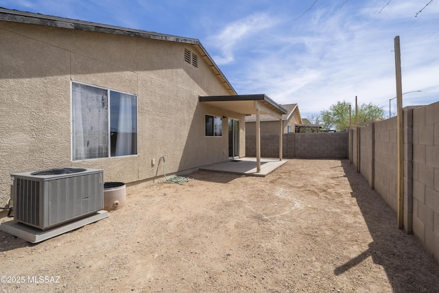 rear view of property featuring stucco siding, central AC, a patio, and a fenced backyard