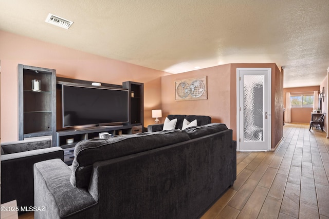 living room with visible vents, wood finished floors, and a textured ceiling