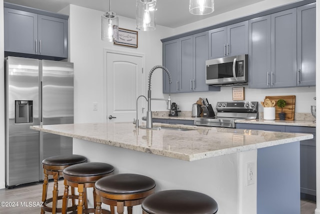 kitchen with a breakfast bar area, light stone countertops, stainless steel appliances, and a sink