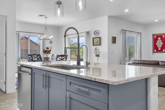 kitchen featuring visible vents, light stone countertops, gray cabinetry, and a center island with sink