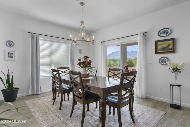 dining area featuring light wood-style flooring, a mountain view, baseboards, and an inviting chandelier