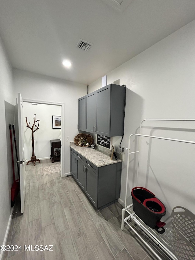 kitchen featuring baseboards, visible vents, gray cabinets, and wood finish floors