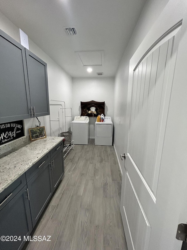 laundry area featuring visible vents, light wood finished floors, attic access, cabinet space, and separate washer and dryer