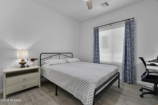 bedroom featuring visible vents, a ceiling fan, baseboards, and wood finished floors