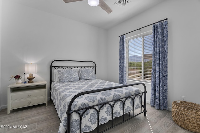 bedroom with ceiling fan, wood finished floors, visible vents, and baseboards