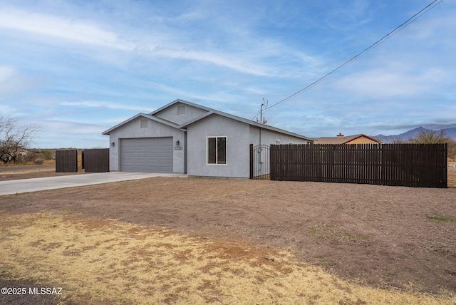 view of home's exterior featuring stucco siding, concrete driveway, a garage, and fence