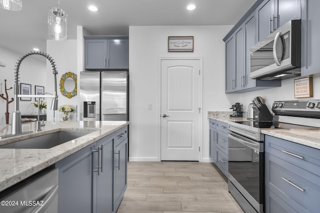 kitchen featuring light stone countertops, recessed lighting, a sink, hanging light fixtures, and stainless steel appliances