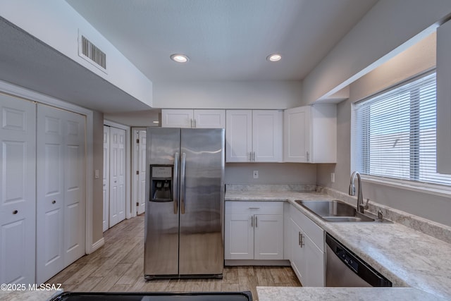 kitchen with visible vents, appliances with stainless steel finishes, white cabinetry, and a sink