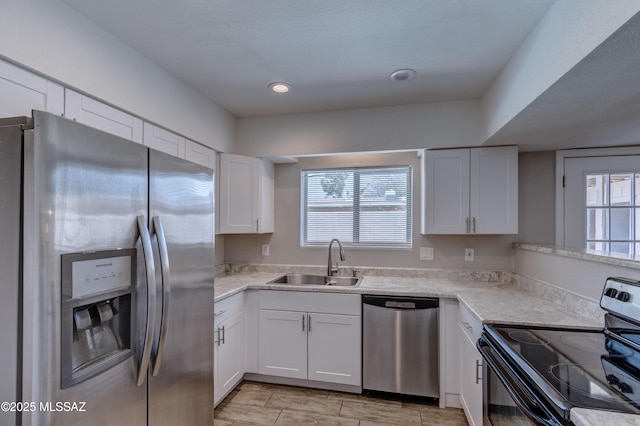 kitchen featuring wood finish floors, a sink, white cabinetry, recessed lighting, and stainless steel appliances