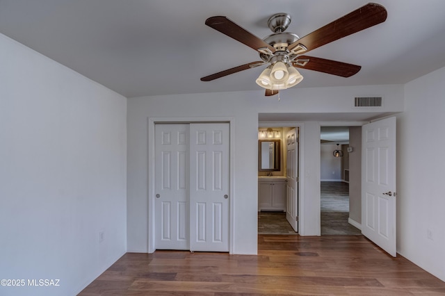 unfurnished bedroom featuring wood finished floors, visible vents, a closet, and ceiling fan