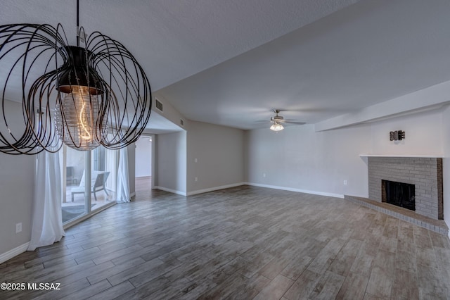 unfurnished living room with visible vents, a fireplace, a ceiling fan, and wood finished floors