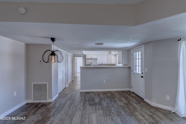 unfurnished living room with visible vents, baseboards, and wood finished floors