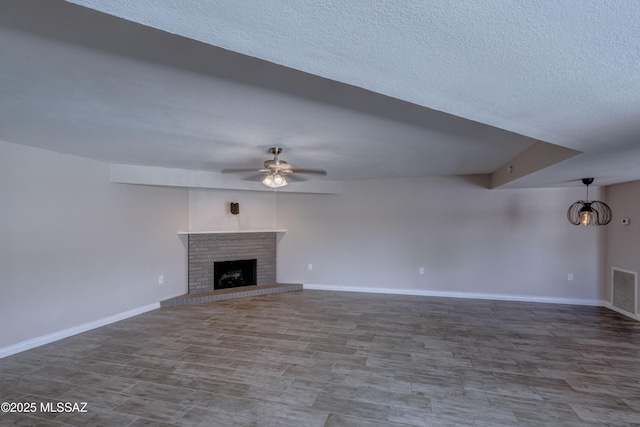 unfurnished living room with visible vents, a ceiling fan, wood finished floors, a fireplace, and baseboards