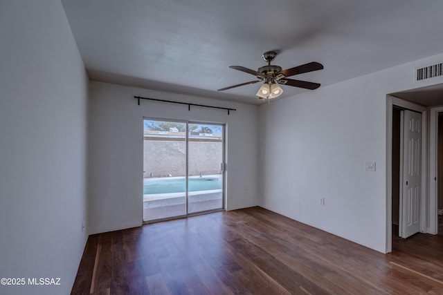 unfurnished room with visible vents, dark wood-style flooring, and ceiling fan