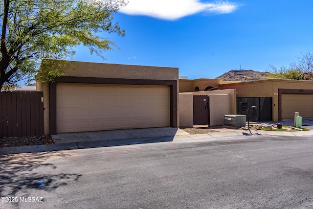 adobe home featuring a gate, stucco siding, a garage, and fence