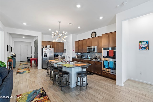 kitchen featuring tasteful backsplash, a kitchen bar, an inviting chandelier, stainless steel appliances, and a sink