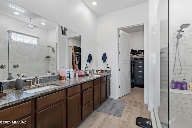 full bathroom with a shower stall, wood finished floors, double vanity, and a sink