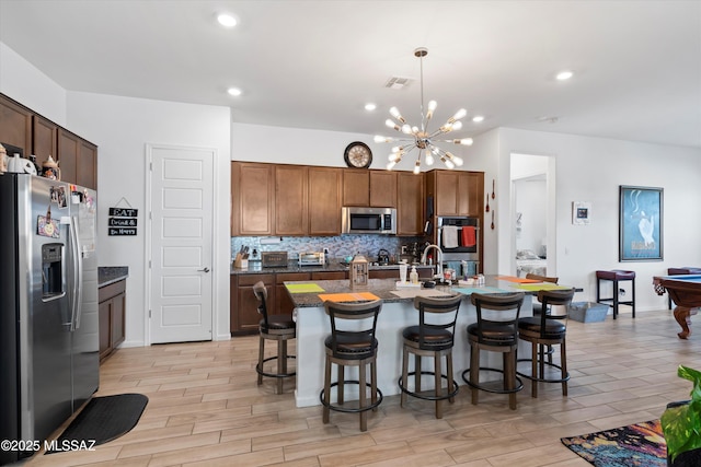 kitchen featuring visible vents, tasteful backsplash, appliances with stainless steel finishes, and a breakfast bar area