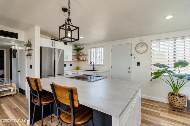 kitchen with light countertops, electric cooktop, stainless steel refrigerator, white cabinets, and open shelves