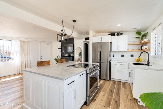 kitchen featuring light wood-style flooring, a sink, stainless steel appliances, white cabinetry, and a center island