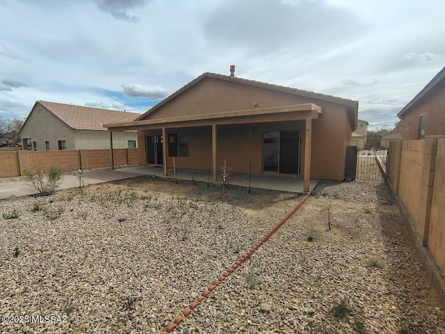 rear view of property with stucco siding, a fenced backyard, and a patio area