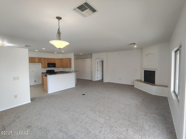 unfurnished living room with recessed lighting, a fireplace with raised hearth, visible vents, and light carpet