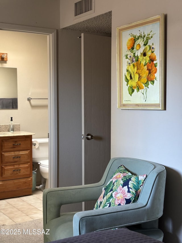 bedroom with visible vents, light tile patterned floors, and ensuite bath