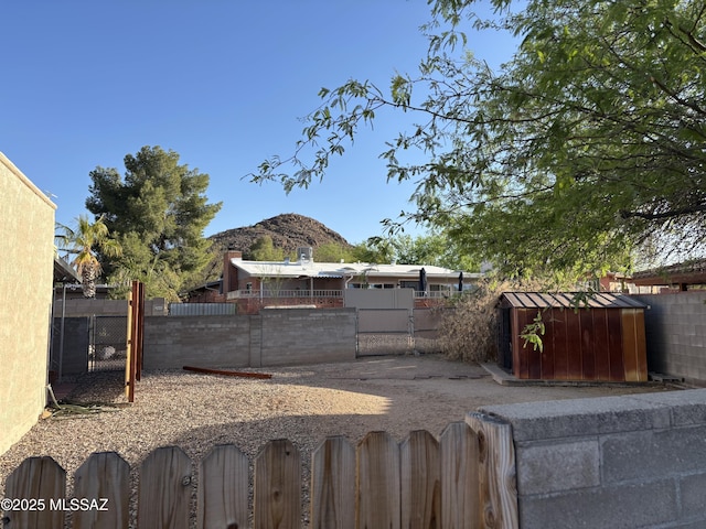 view of yard with a storage shed, an outbuilding, a mountain view, and fence private yard
