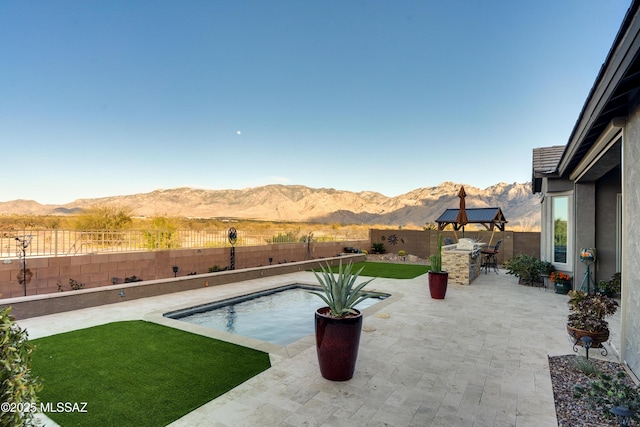 view of pool with a patio, a yard, a fenced backyard, and a mountain view