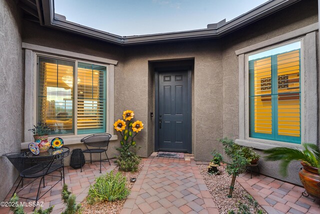 property entrance with a patio area and stucco siding